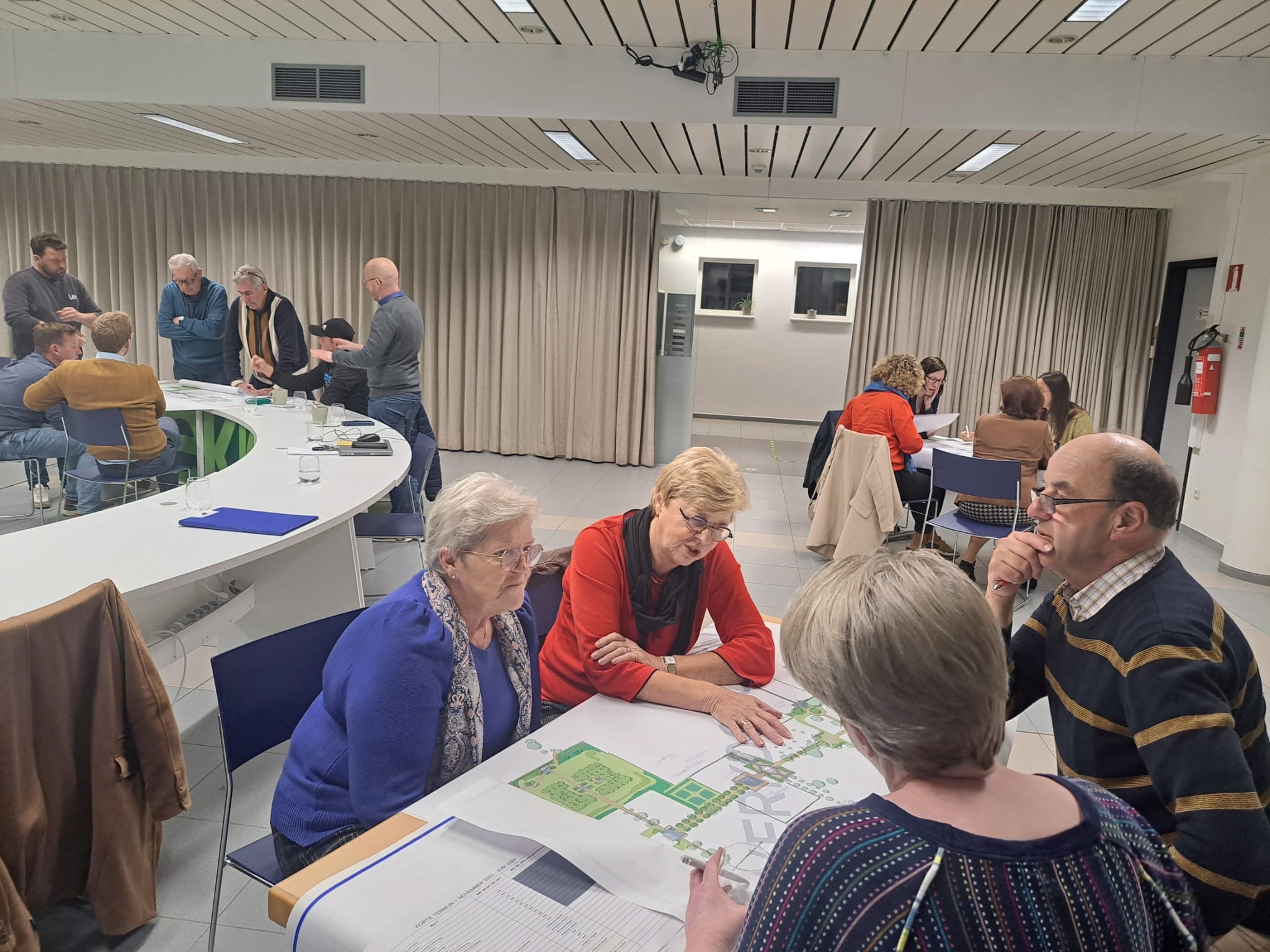 Deelnemers bespreken kaarten en ideeën voor de begraafplaats in kleine groepen.