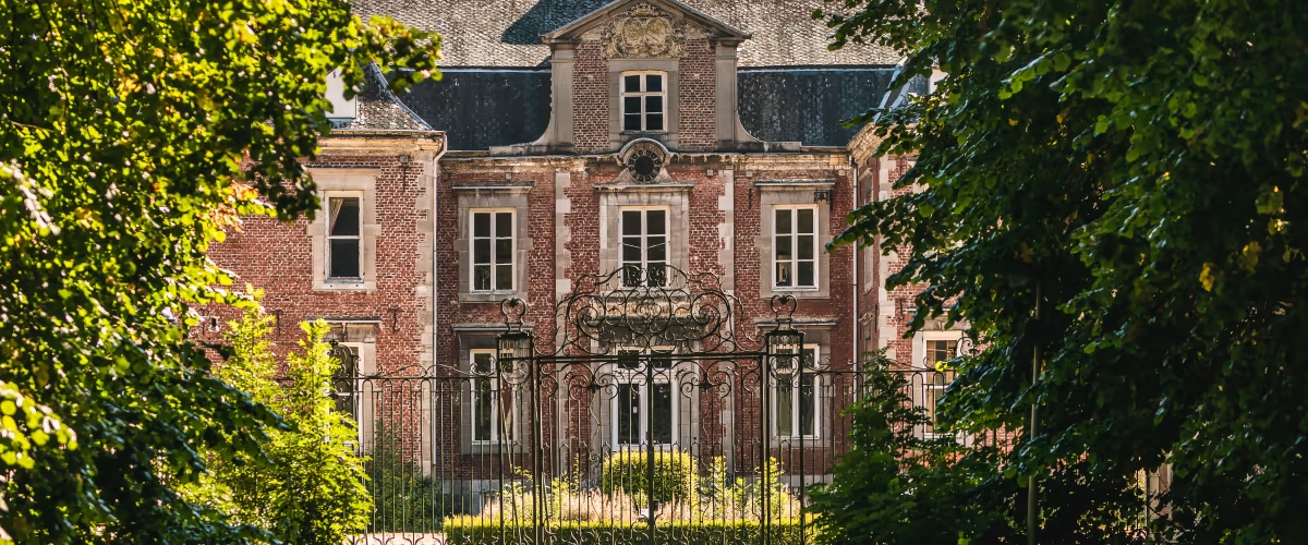 Het kasteel van Leut achter de toegangspoort, omringd door groen.